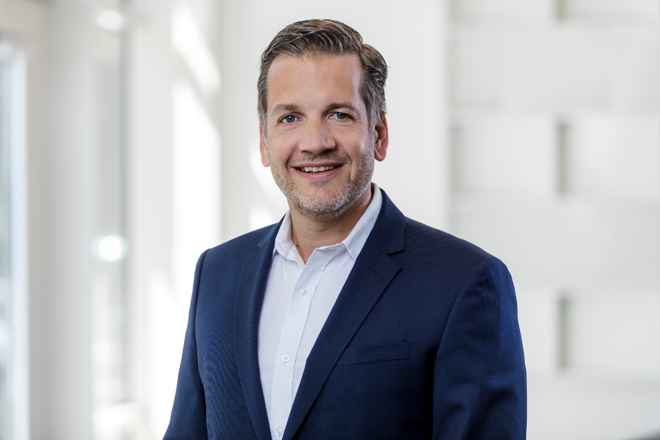 Porträt eines Mannes in einem blauen Anzug mit einem freundlichen Lächeln.