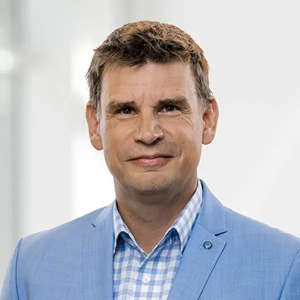 Porträt von Andy McBrine in einem hellblauen Anzug mit kariertem Hemd.