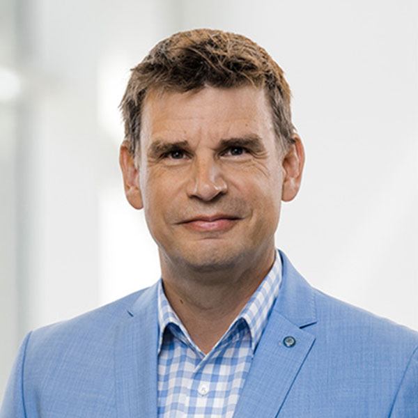 Porträt von Andy McBrine in einem hellblauen Anzug mit kariertem Hemd.