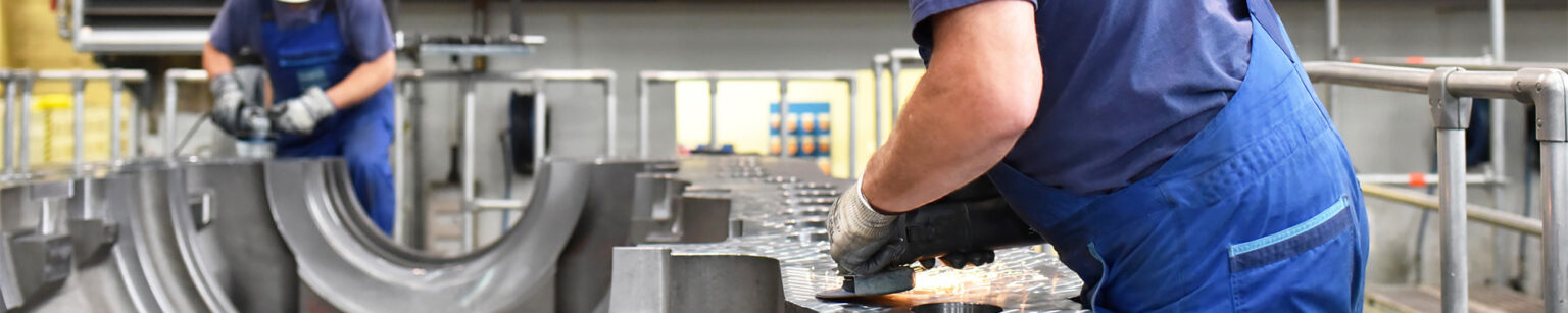 Arbeiter, der an einem Metallteil im Maschinenbau mit einer Schleifmaschine arbeitet.