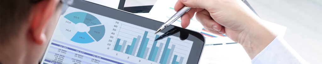 Person, die mit einem Stift auf ein Tablet mit Geschäftsdaten und Diagrammen zeigt.