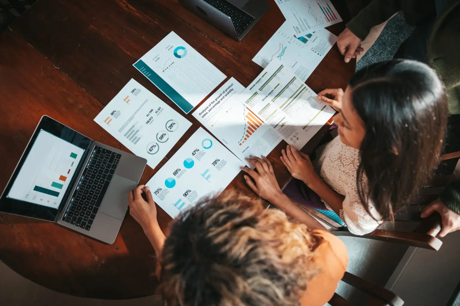 Personen analysieren Geschäftsdaten und Diagramme auf einem Tisch mit Laptops und Dokumenten.