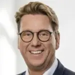 Porträt eines Mannes mit Brille und blondem Haar, der lächelt.