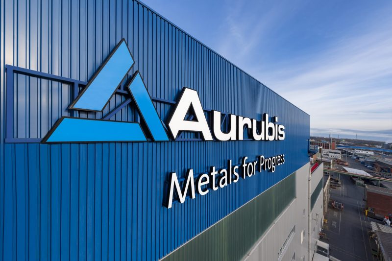Das Logo von Aurubis auf der Fassade eines Unternehmensgebäudes in blauer Farbe.