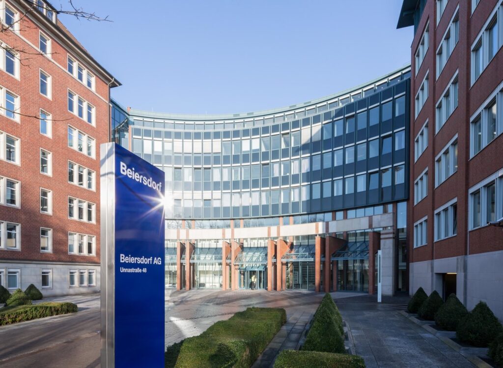 Eingang zur Beiersdorf AG Zentrale in Hamburg mit modernem Gebäude und Firmenlogo.
