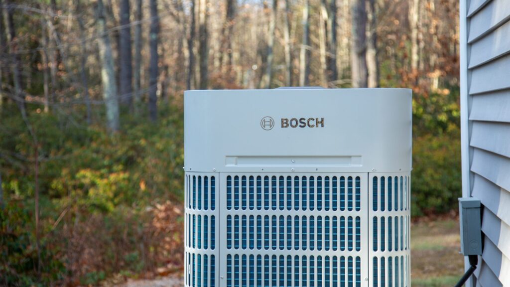 Klimaanlage von Bosch, sichtbar in einem Gartenbereich mit Bäumen im Hintergrund.