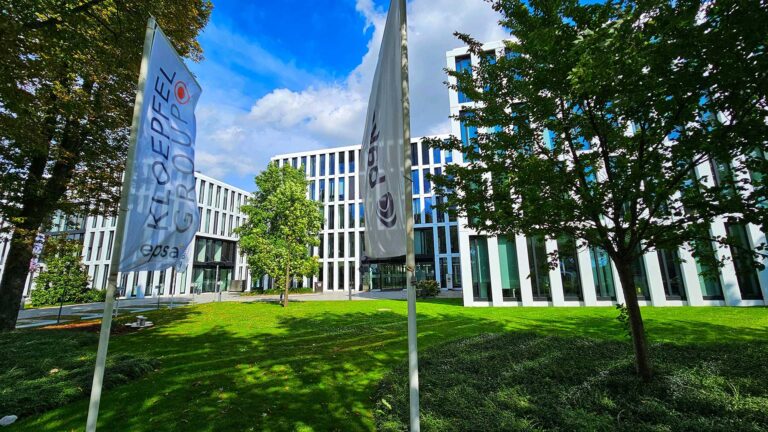 Moderne Bürogebäude der KLOEPFEL Gruppe mit EPSA-Logo und Fahnen im Vordergrund.