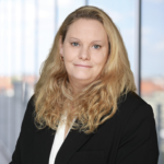 Porträt von Denise Roggenbuck mit langen, lockigen Haaren und einem schwarzen Blazer.