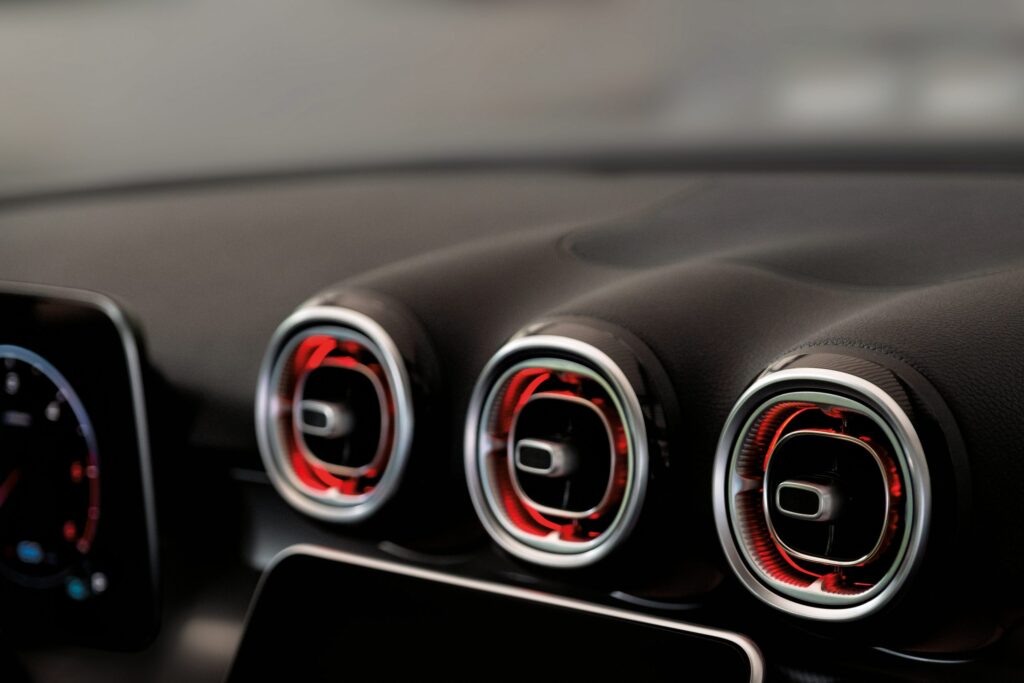 Drei runde Lüftungsdüsen in einem Fahrzeug mit rotem Akzentlicht.