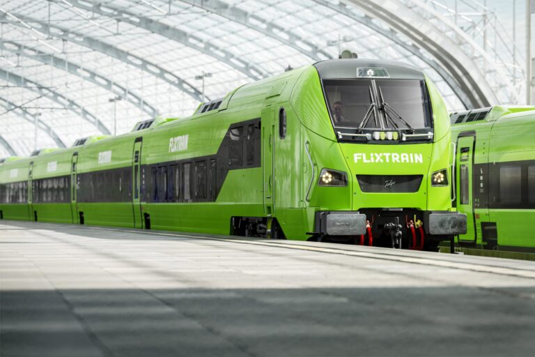 Grüner FlixTrain, der am Bahnhof steht, mit sichtbarem Logo und moderner Zugdesign.
