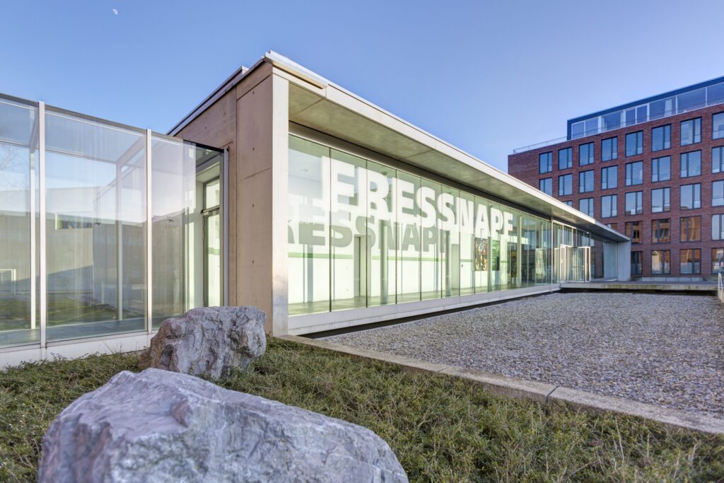 Moderne Glasfassade des Fressnapf Gebäudes mit klaren Linien und Steinlandschaft.