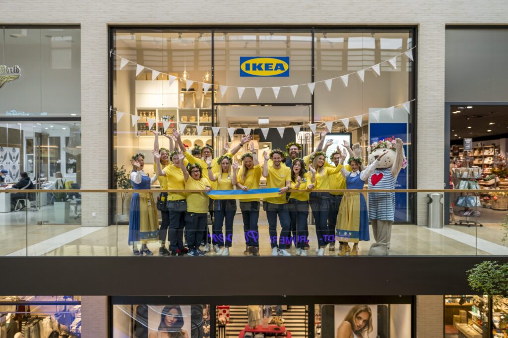 Gruppe von IKEA Mitarbeitern in gelben T-Shirts im Planungsstudio Rheine, die fröhlich posieren.