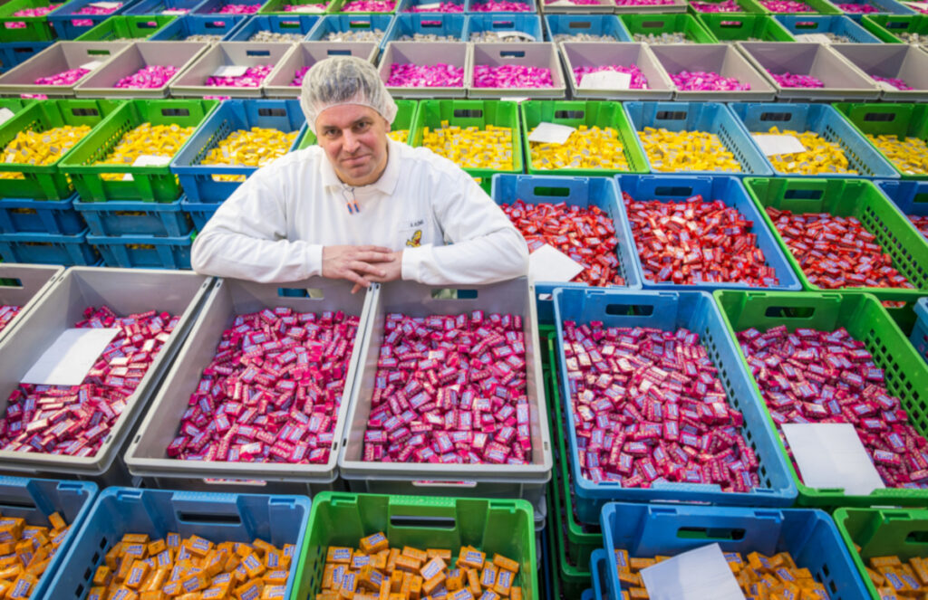 Ein Mitarbeiter in einem Produktionswerk mit bunten MAOAM-Süßigkeiten in Kisten.
