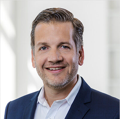 Portrait de Marc Kloepfel en costume avec une expression souriante.