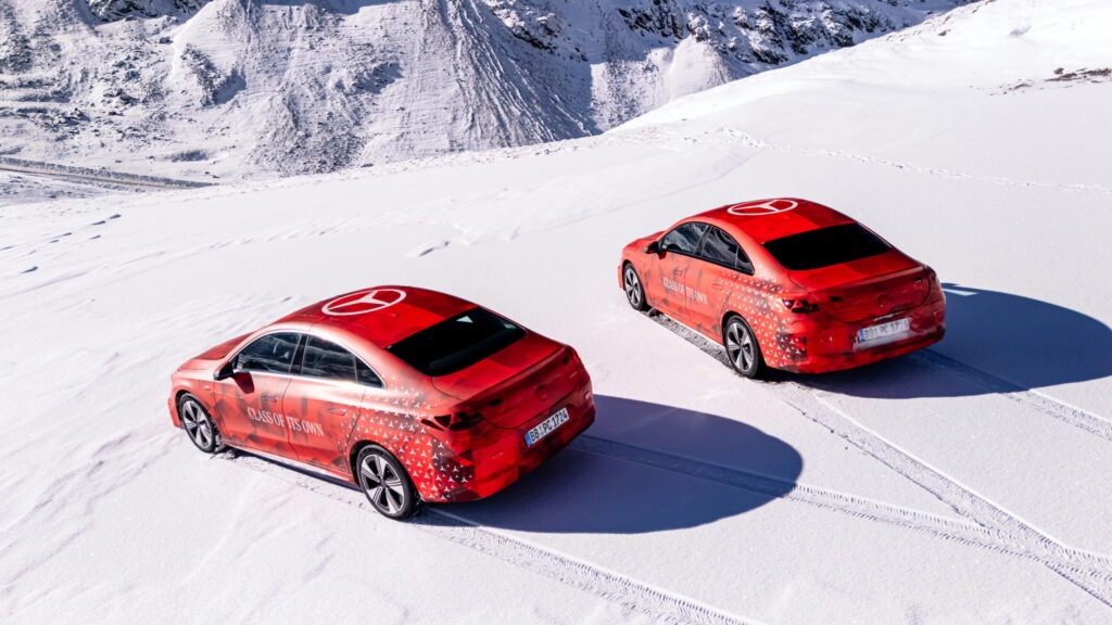 Zwei rote Mercedes-Benz Fahrzeuge mit Schneemuster auf einer verschneiten Fläche.