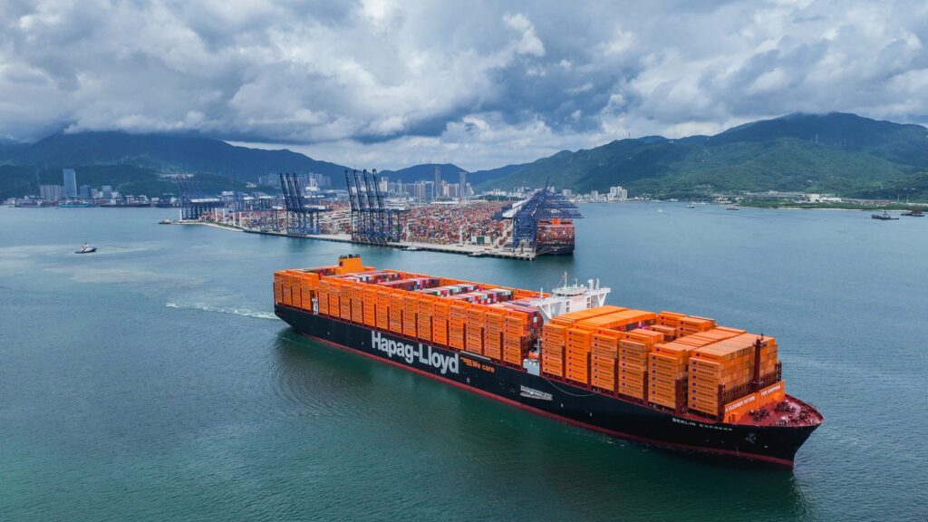 Containerschiff von Hapag-Lloyd mit orangefarbenen Containern im Hafen.