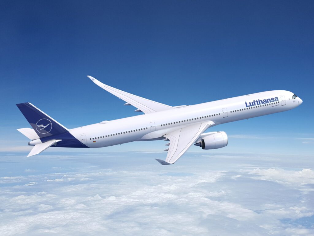 Ein Lufthansa Flugzeug fliegt über den Wolken in einem klaren blauen Himmel.