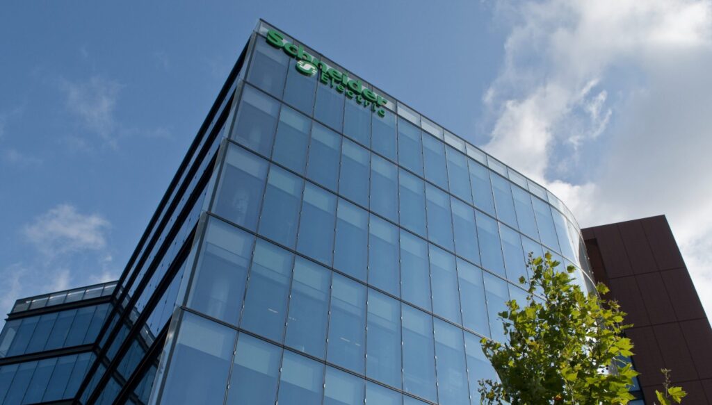 Moderne Bürogebäude mit Glasfassade und Schneider Electric Logo auf dem Dach.