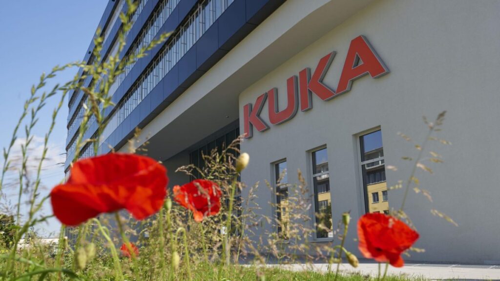 Fassade des KUKA Gebäudes in Augsburg mit roten Mohnblumen im Vordergrund.