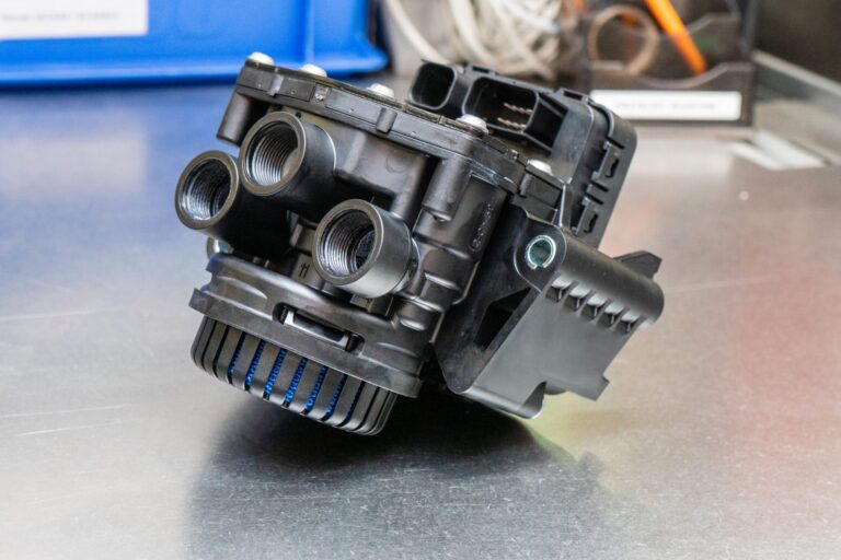Luftfiltergehäuse mit mehreren Anschlüssen auf einer metallischen Oberfläche.