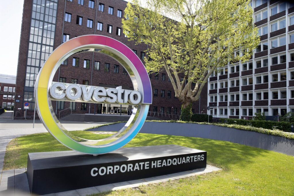 Logo von Covestro an der Unternehmenszentrale mit buntem Ring und Schriftzug.