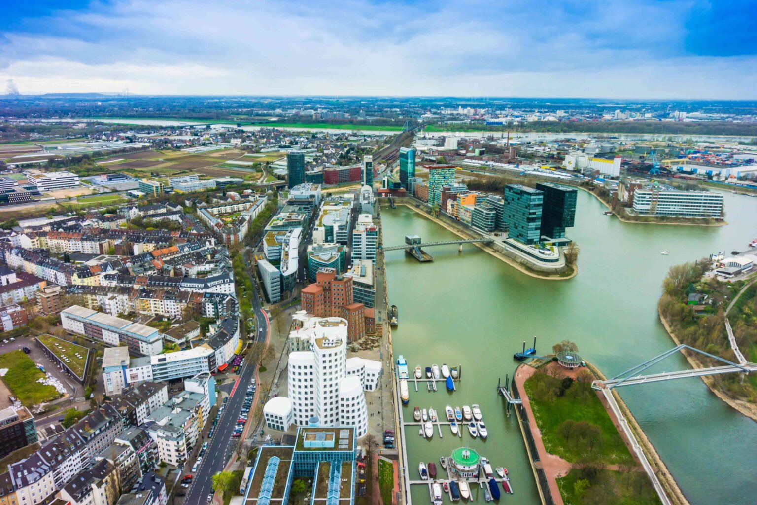 Luftaufnahme der Stadt Düsseldorf mit modernen Gebäuden und einem Fluss im Vordergrund.