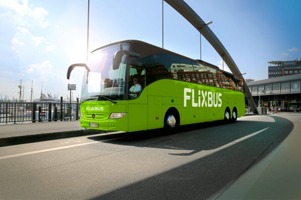 Grüner FlixBus Reisebus auf einer Straße mit einem Fahrer im Cockpit.
