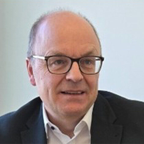 Porträt eines Mannes mit Brille, der in die Kamera lächelt.
