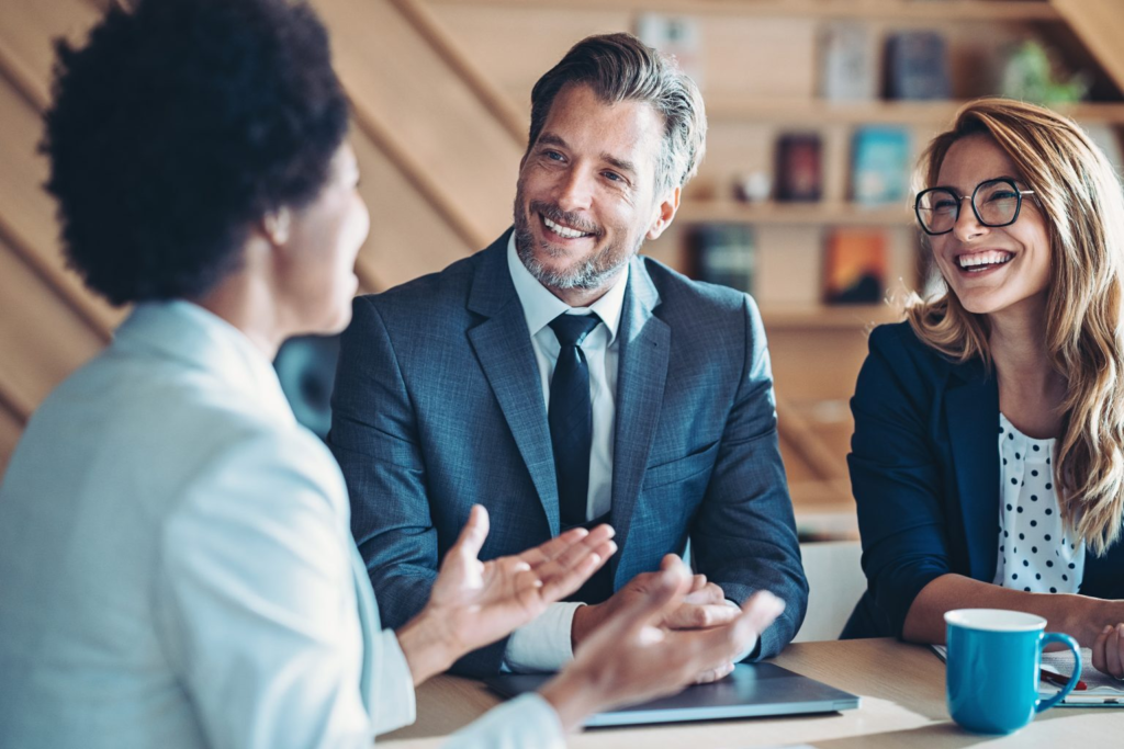 Trois personnes en tenue formelle qui se parlent dans un bureau moderne.