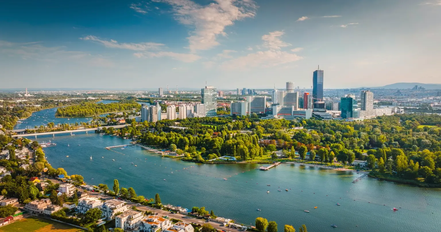 Luftaufnahme einer Stadt mit Wasser, Bäumen und modernen Gebäuden.