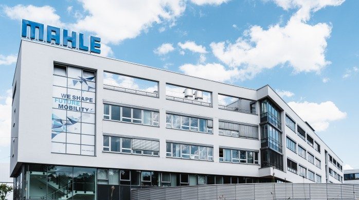 Fassade des Hauptsitzes von MAHLE mit dem Slogan 'WE SHAPE FUTURE MOBILITY'.