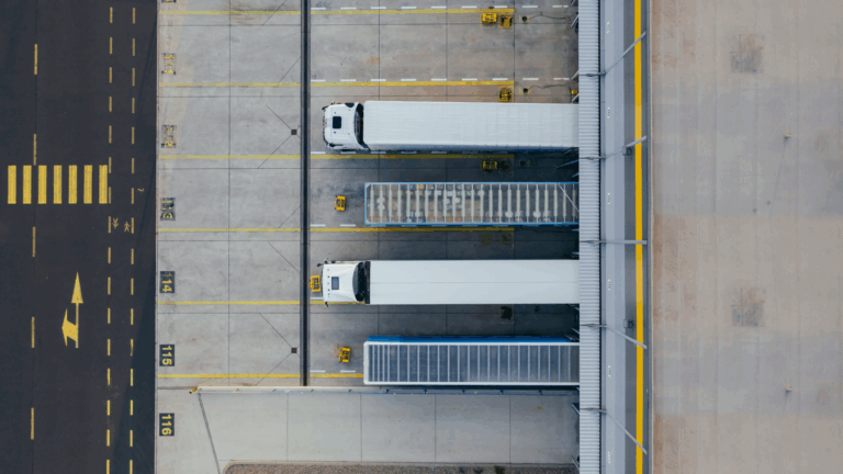 Luftaufnahme eines Logistikzentrums mit mehreren Lkw in Ladebereichen.