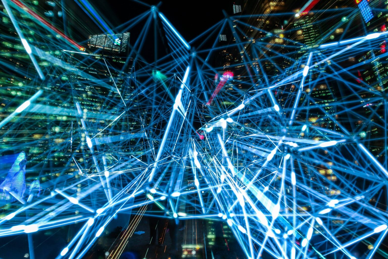 Visualisierung eines Netzwerks mit blauen Lichtlinien, die über eine Stadtlandschaft verteilt sind.
