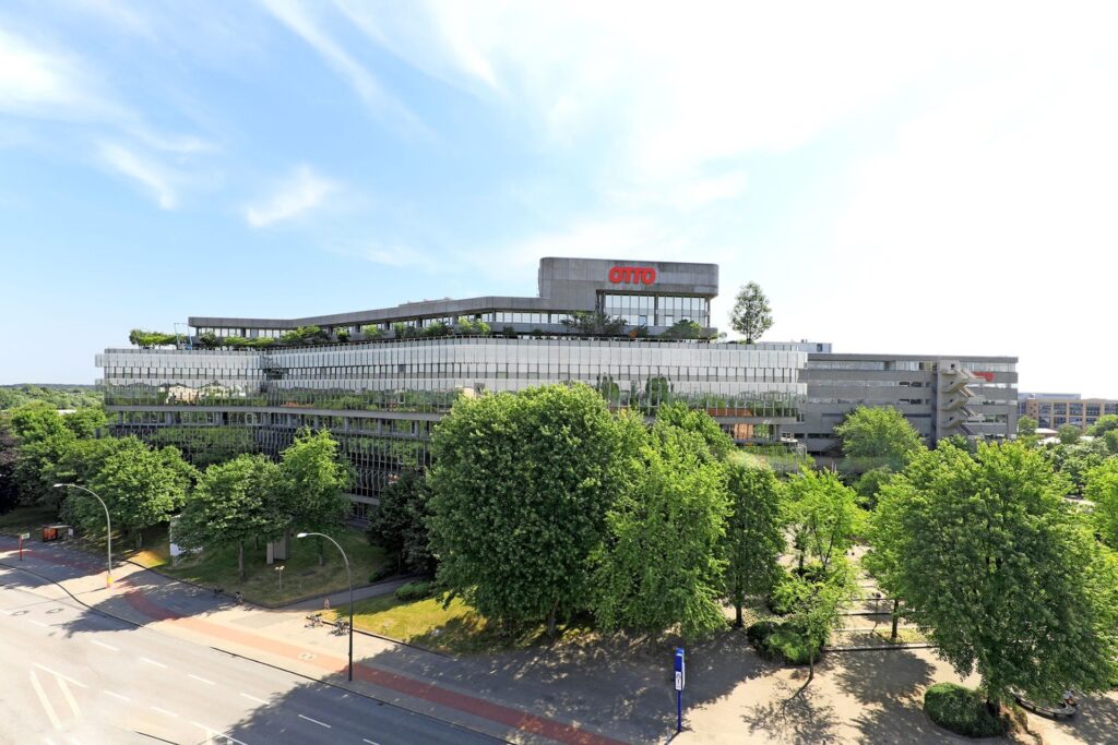 Moderne Bürogebäude des Otto Group Campus mit grünen Bäumen im Vordergrund.