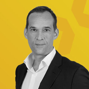 Schwarz-weiß Porträt von Patrick Esselborn vor gelbem Hintergrund.