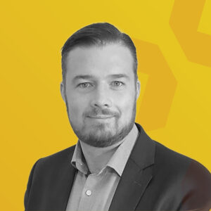 Schwarz-weiß-Porträt von Ingo Glawe vor gelbem Hintergrund.