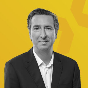 Schwarz-weiß-Porträt von Alexander Hornikel vor gelbem Hintergrund.