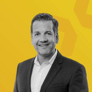 Porträt von Marc Kloepfel vor einem gelben Hintergrund.