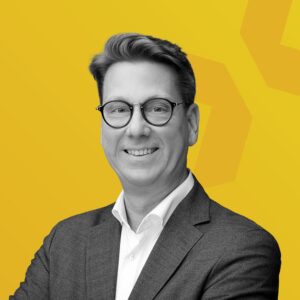 Schwarz-weiß Porträt von Andreas Miltzner mit gelbem Hintergrund.