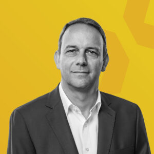 Schwarz-weiß Porträt von Marcus Schilling vor gelbem Hintergrund.