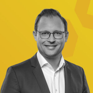 Schwarz-weiß-Porträt von Heiko Steinmetz vor gelbem Hintergrund.