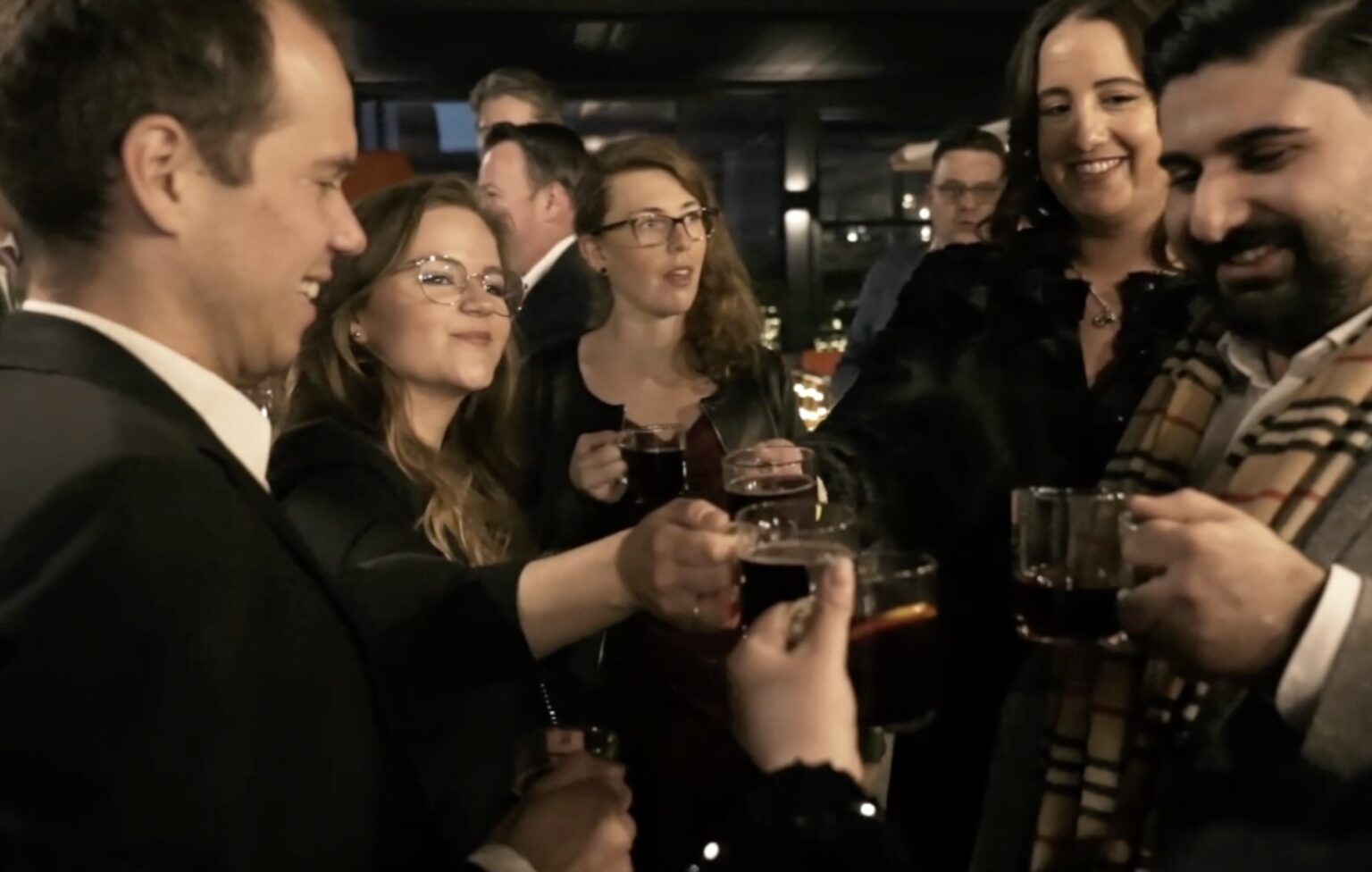 Eine Gruppe von Personen, die mit Gläsern anstoßen und Getränke halten.