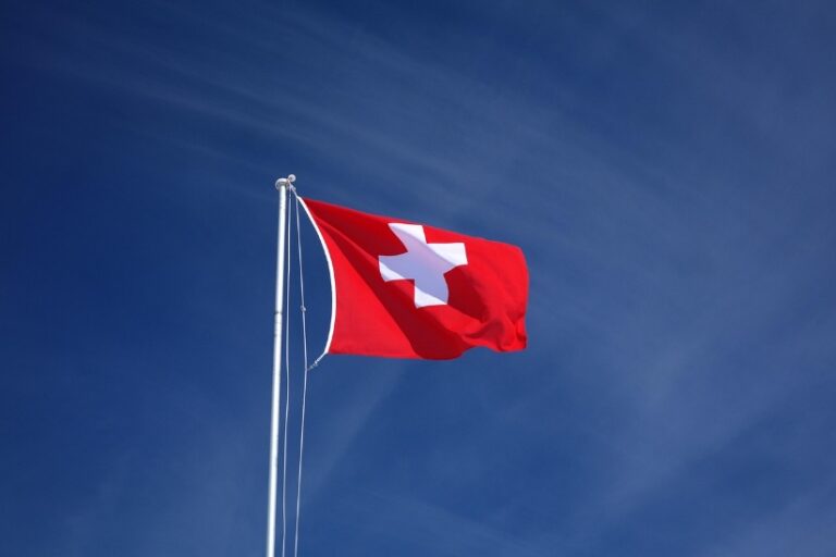 Rote Flagge mit weißem Kreuz, die im Wind weht.