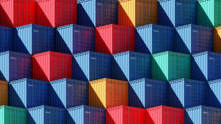 Conteneurs de fret empilés de différentes couleurs, dont le rouge, le bleu, le vert et le jaune.