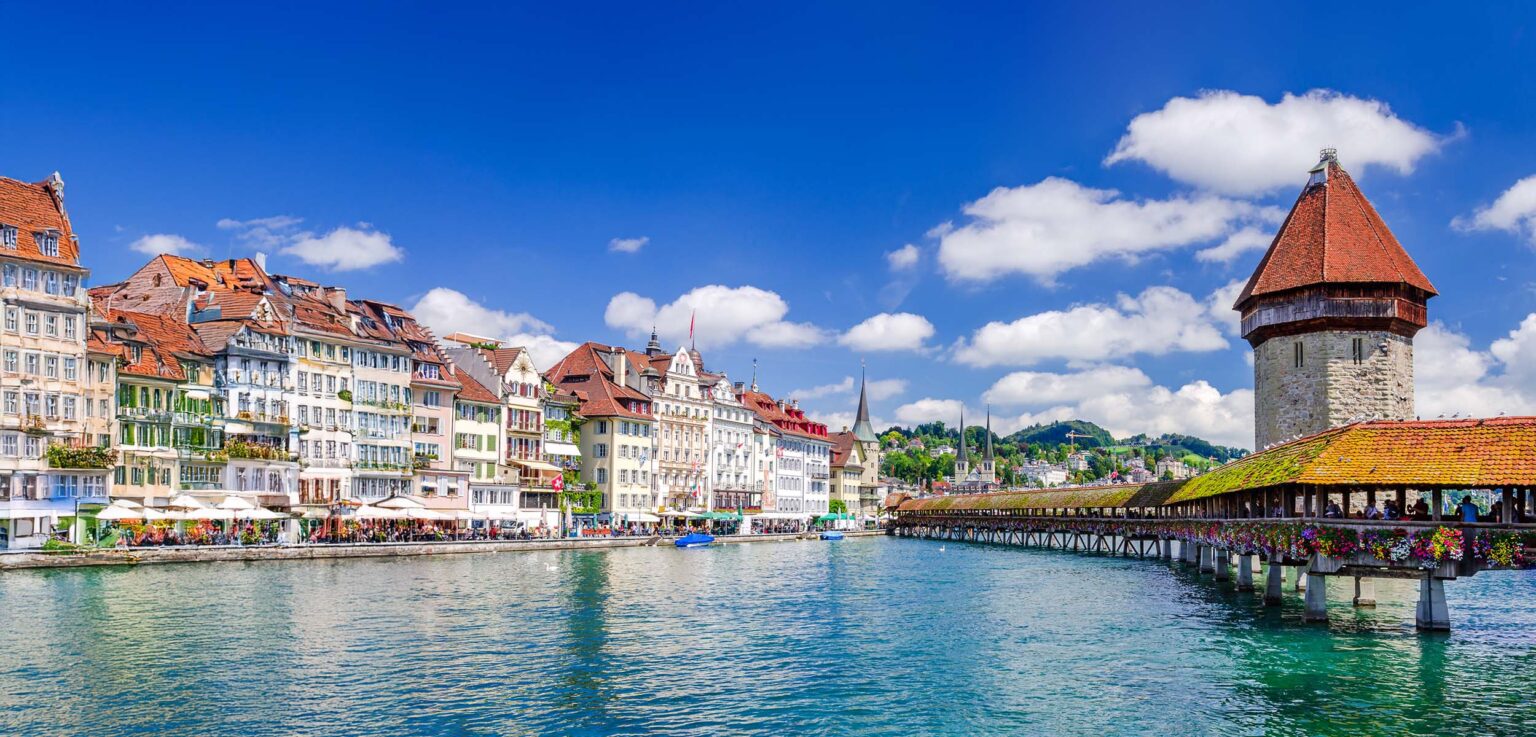 Stadtansicht von Luzern mit der Kapellbrücke und historischen Gebäuden am Ufer.