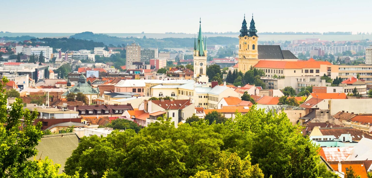 Blick auf die Stadt Nitra mit roten Dächern und markanten Kirchen im Hintergrund.