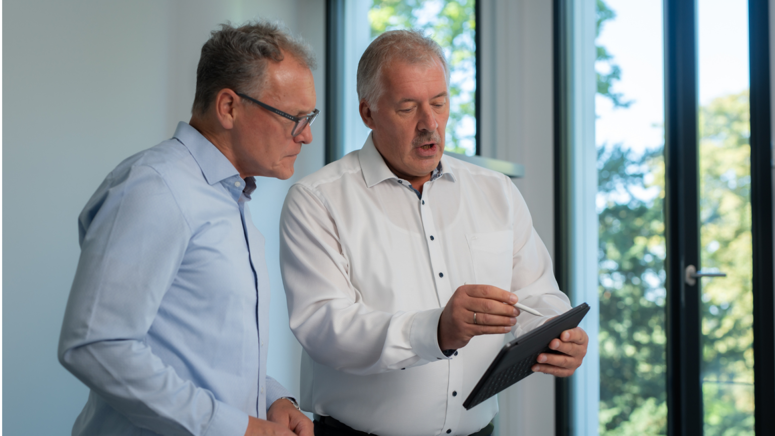 Two experts discuss a technical device during a meeting in a modern office.