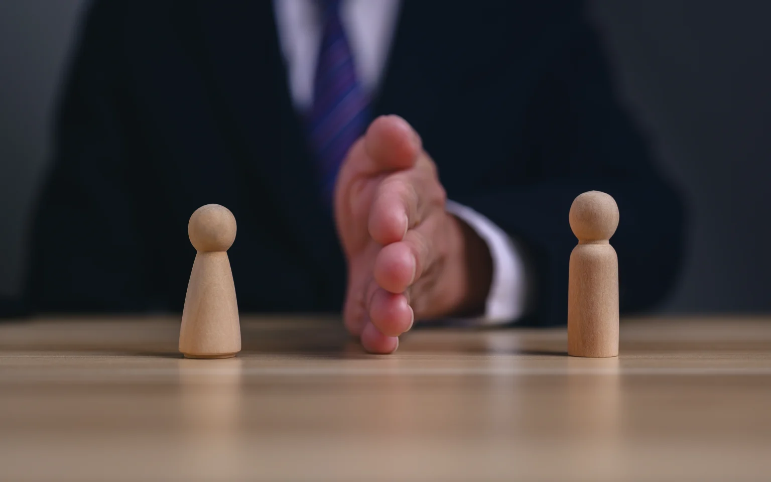 Strategischer Einkauf - Geschäftsmann mit zwei strategischen Spielfiguren sitzend an einem Schreibtisch