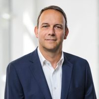 Porträt eines Mannes in Anzug Porträt eines Mannes in einem dunklen Anzug mit einem weißen Hemd vor einem neutralen Hintergrund.